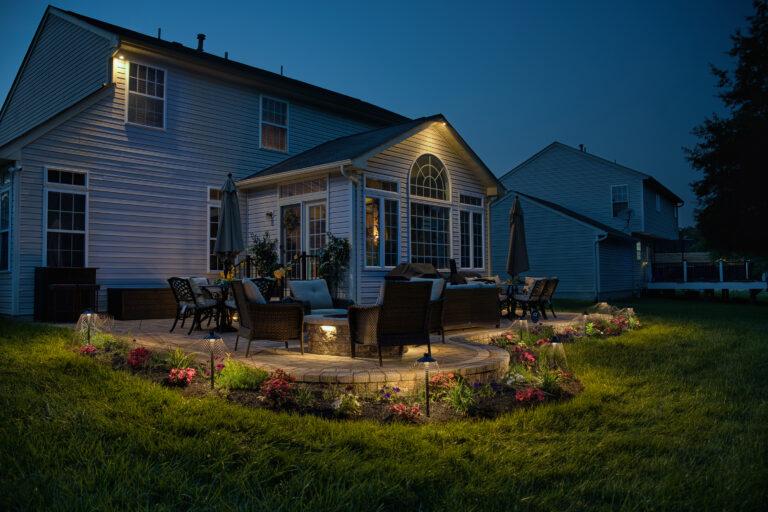 Outdoor seating area with landscape lighting surrounding a patio and fire pit